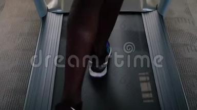 穿着蓝色运动鞋的非裔美国运动员在健身俱乐部的电动跑步机上锻炼。不要脸的男跑步者